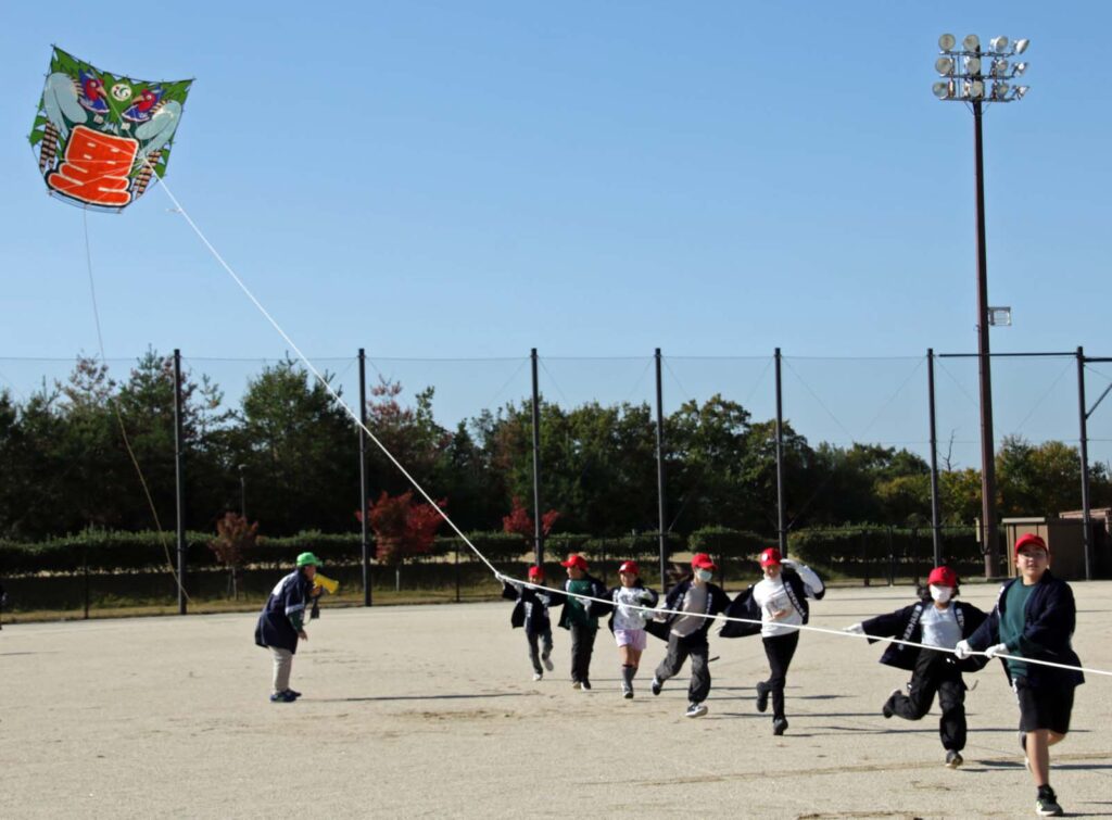大空をめざして飛び始めた8畳敷大凧と走るメンバー